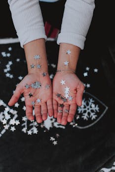 特写镜头中，手与银星五彩纸屑营造出神奇的冬日氛围