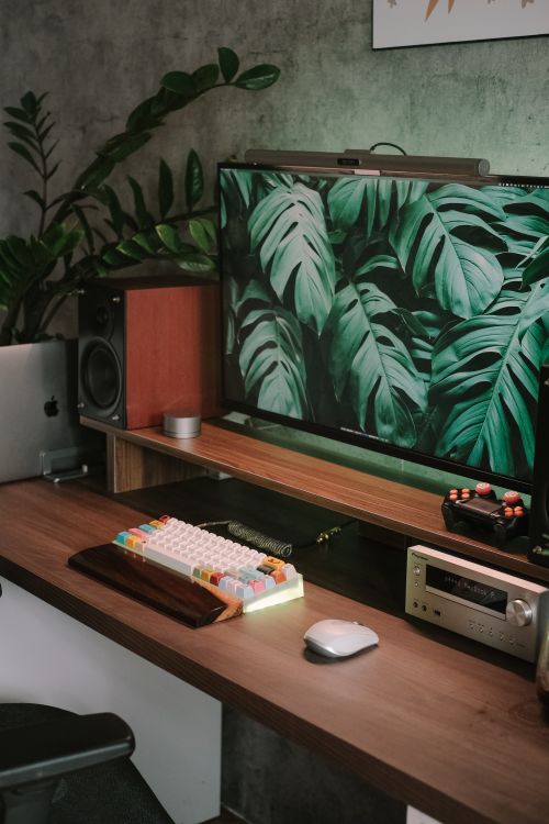 Free Stylish home office featuring a computer, keyboard, and lush green decor for a fresh workspace. Stock Photo