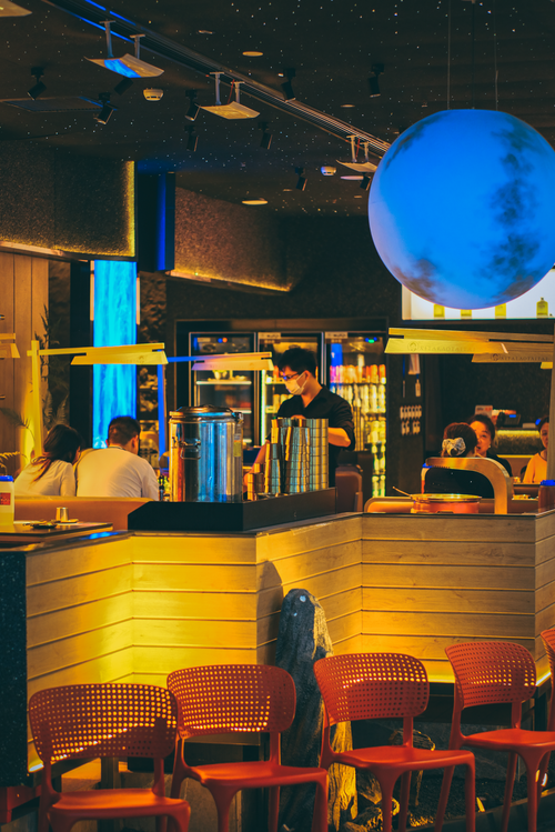 Free A stylish cafe with vibrant lighting and a unique blue sphere installation, creating a cozy ambiance. Stock Photo