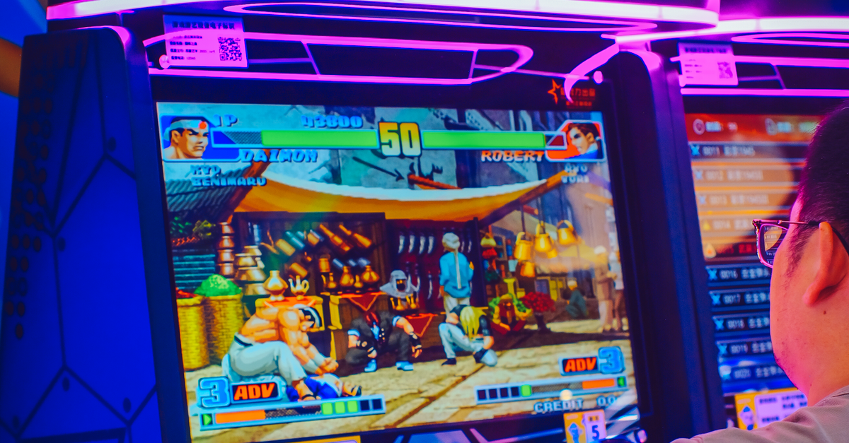 Player Enjoying Arcade Game with Neon Lights · Free Stock Photo