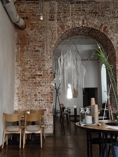 Cafe interior with an exposed brick arch and pale timber chairs — photo by Larisa Kruchina on Pexels