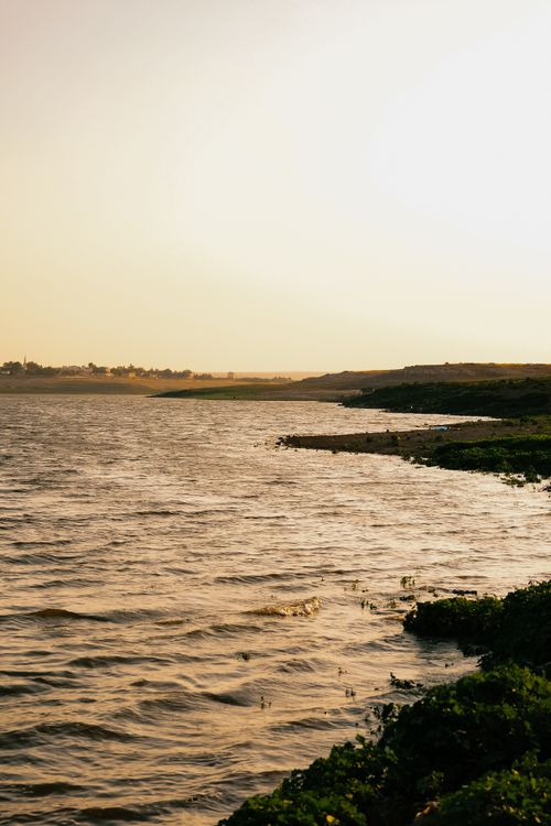 Free Peaceful evening by the lake with gentle waves and warm sunset glow. Stock Photo