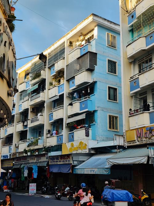 Free Colorful residential building with street vendors and locals during sunset in an urban cityscape. Stock Photo