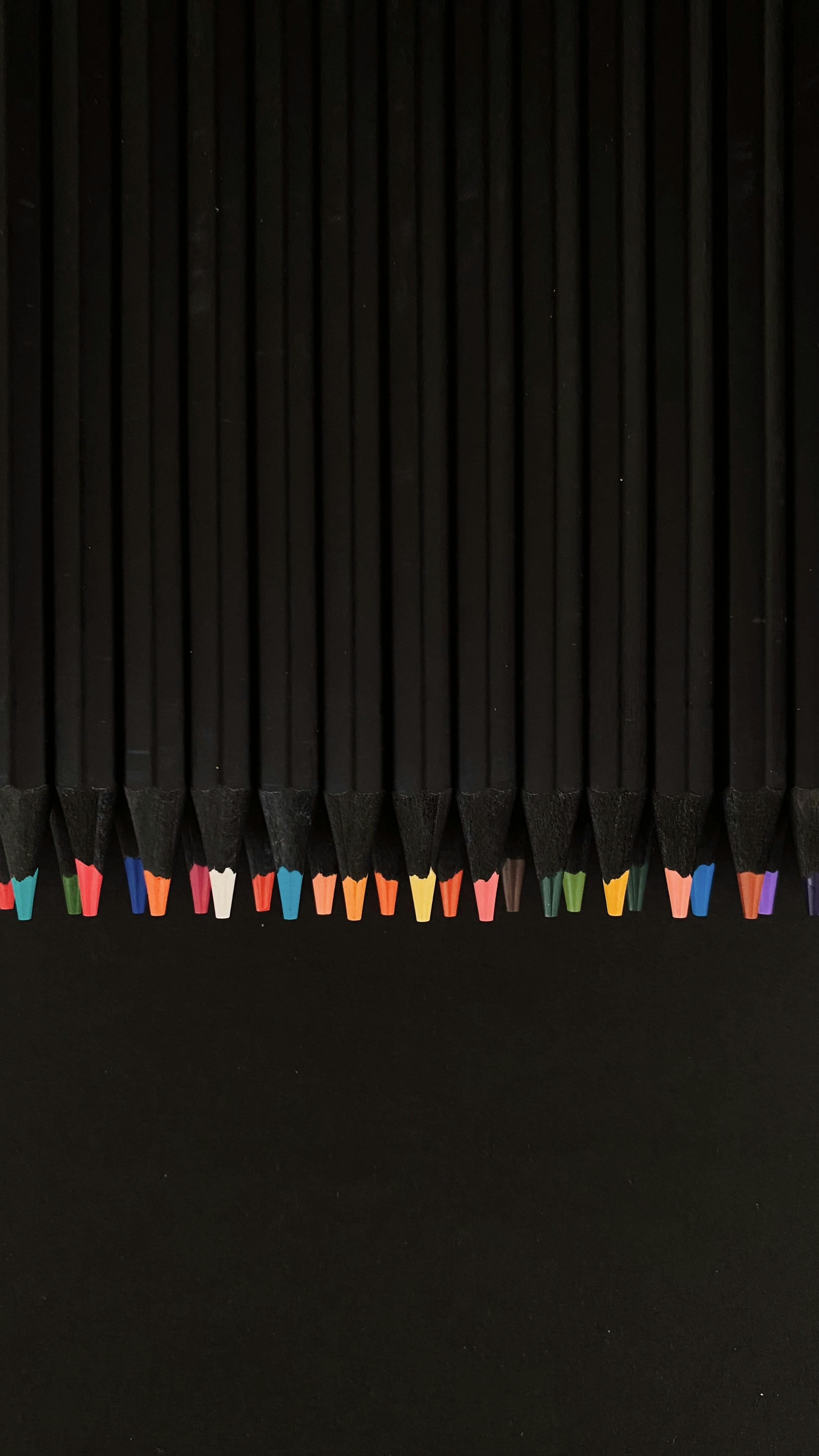 grátis Arranjo vertical de pontas de lápis coloridas sobre uma superfície preta, exibindo materiais de arte. Foto profissional