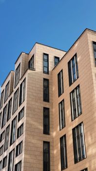 A modern urban building with tall windows under a clear blue sky.