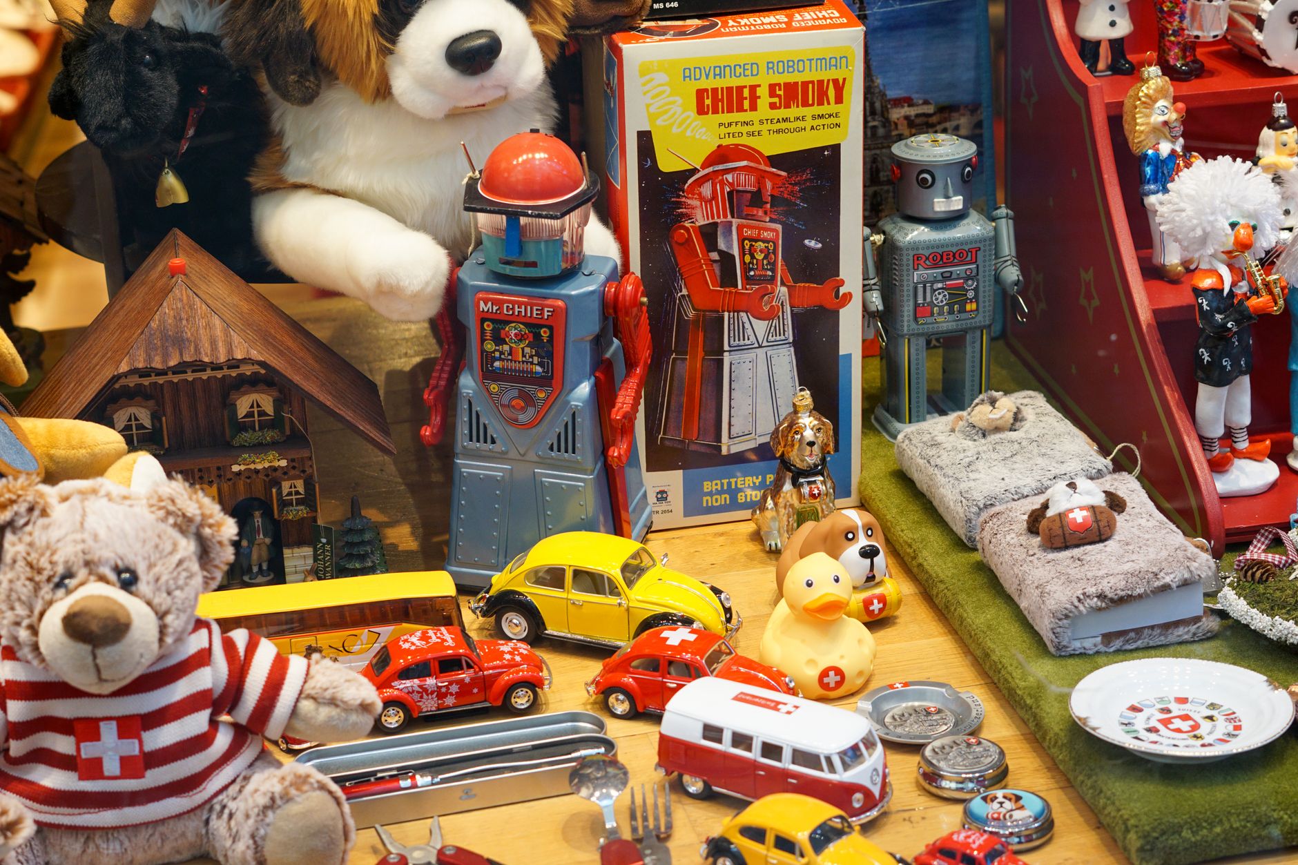 Colorful collection of vintage toys in a Basel shop window display, including robots and toy cars.