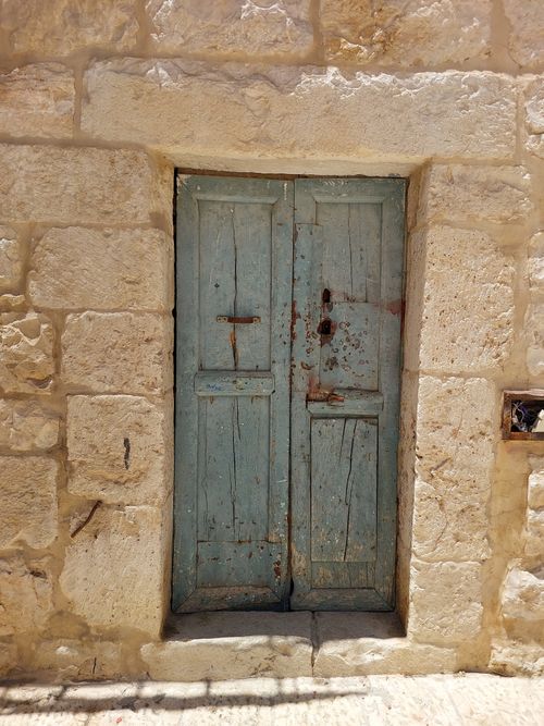 Free Explore the textured charm of an old blue door set in Bethlehem's historic stone walls. Stock Photo