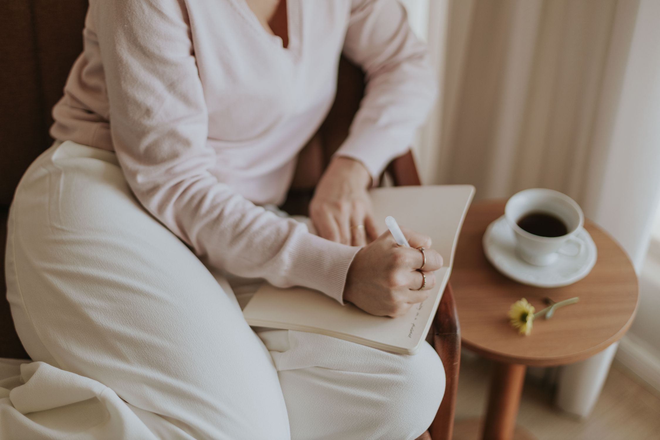 Uma pessoa escrevendo um diário em uma sala aconchegante com uma xícara de café. Ambiente acolhedor e convidativo.
