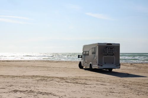 Free A peaceful scene with a camper van parked on a sandy Danish beach by the North Sea. Stock Photo