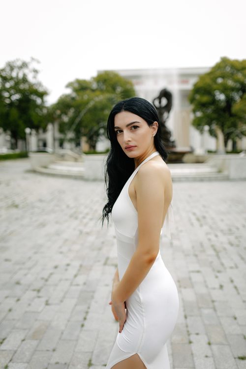 Free Stunning fashion portrait of a woman in white dress in a historic city square. Stock Photo