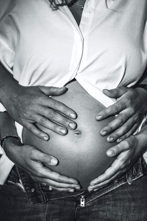 Free Close-up of expectant couple's hands on pregnant belly, symbolizing togetherness and family love. Stock Photo