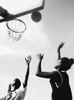Black and white photo of women playing outdoor basketball, capturing dynamic motion and teamwork.