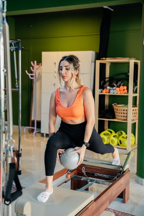 Free Fitness enthusiast performing reformer pilates exercises with equipment in a modern indoor studio. Stock Photo