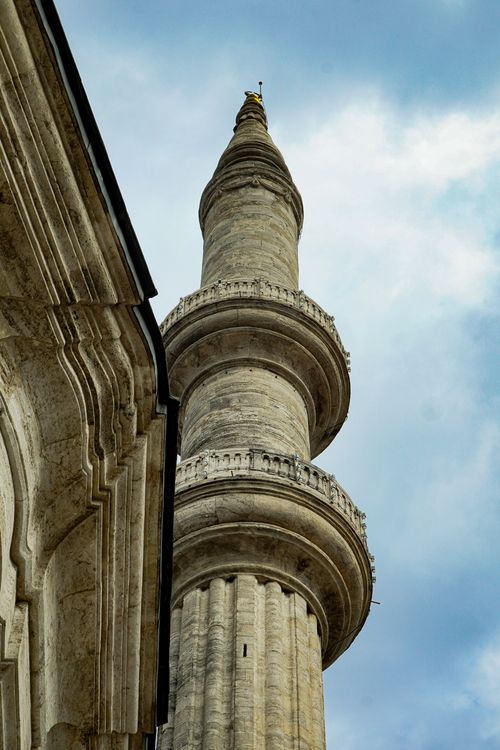 Free Vertical shot of a historical stone minaret towering against a partly cloudy sky, showcasing architectural beauty. Stock Photo