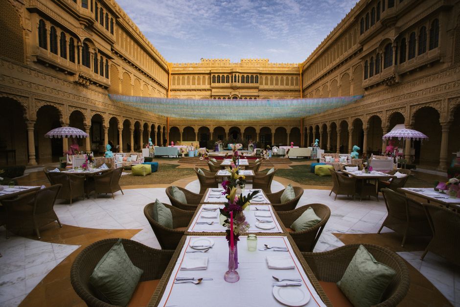 Elegant outdoor dining arrangement in a historic courtyard with decorated tables and ambient lighting.