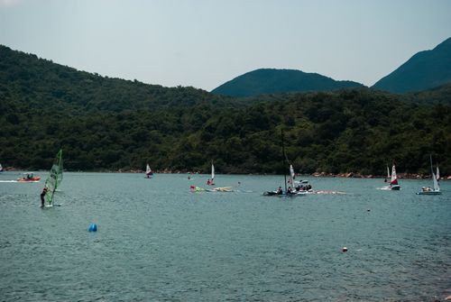 Free Enjoy windsurfing and sailing in Hong Kong's picturesque waters, framed by lush green hills. Stock Photo