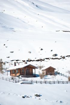 Rustic wooden cabin surrounded by snow in a serene winter landscape, offering a tranquil retreat.