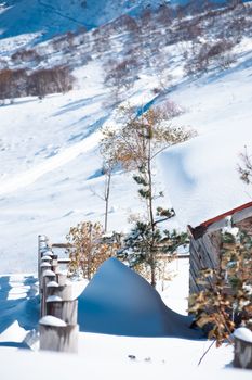 A serene snowy landscape featuring a rustic cabin and snow-covered mountains, capturing a winter wonderland.