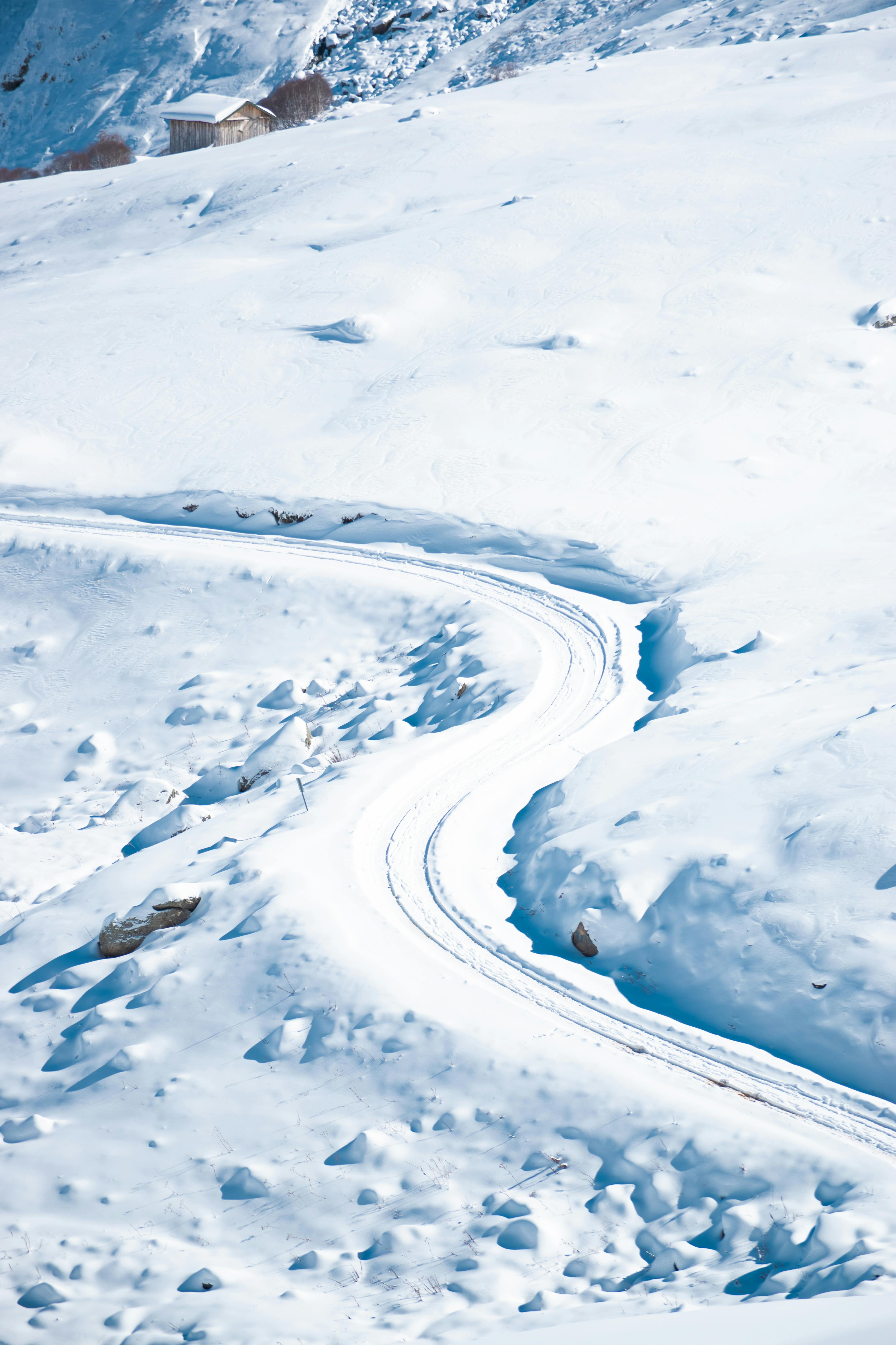 A winding road through a snowy mountain landscape under a clear winter sky.