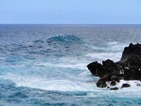 A stunning view of waves crashing against volcanic rocks in Porto Moniz, Madeira, Portugal.