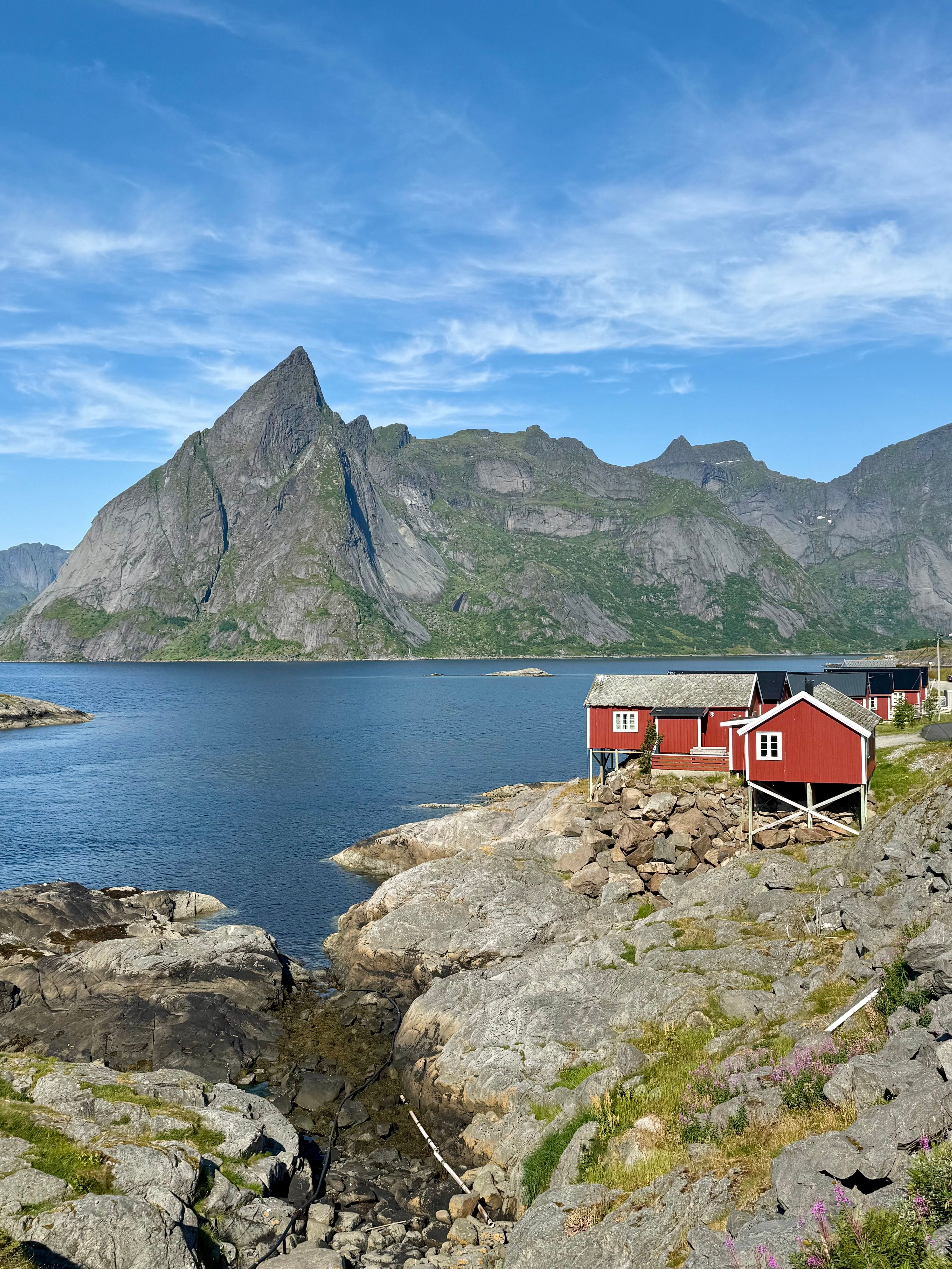 A red rorbuer cabin on granite rock above the water in Reine, Lofoten.