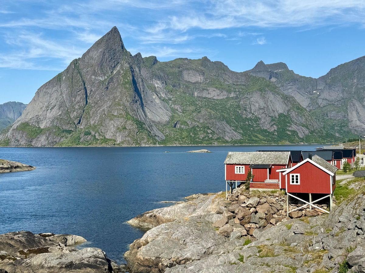 A red rorbuer cabin on granite rock above the water in Reine, Lofoten.