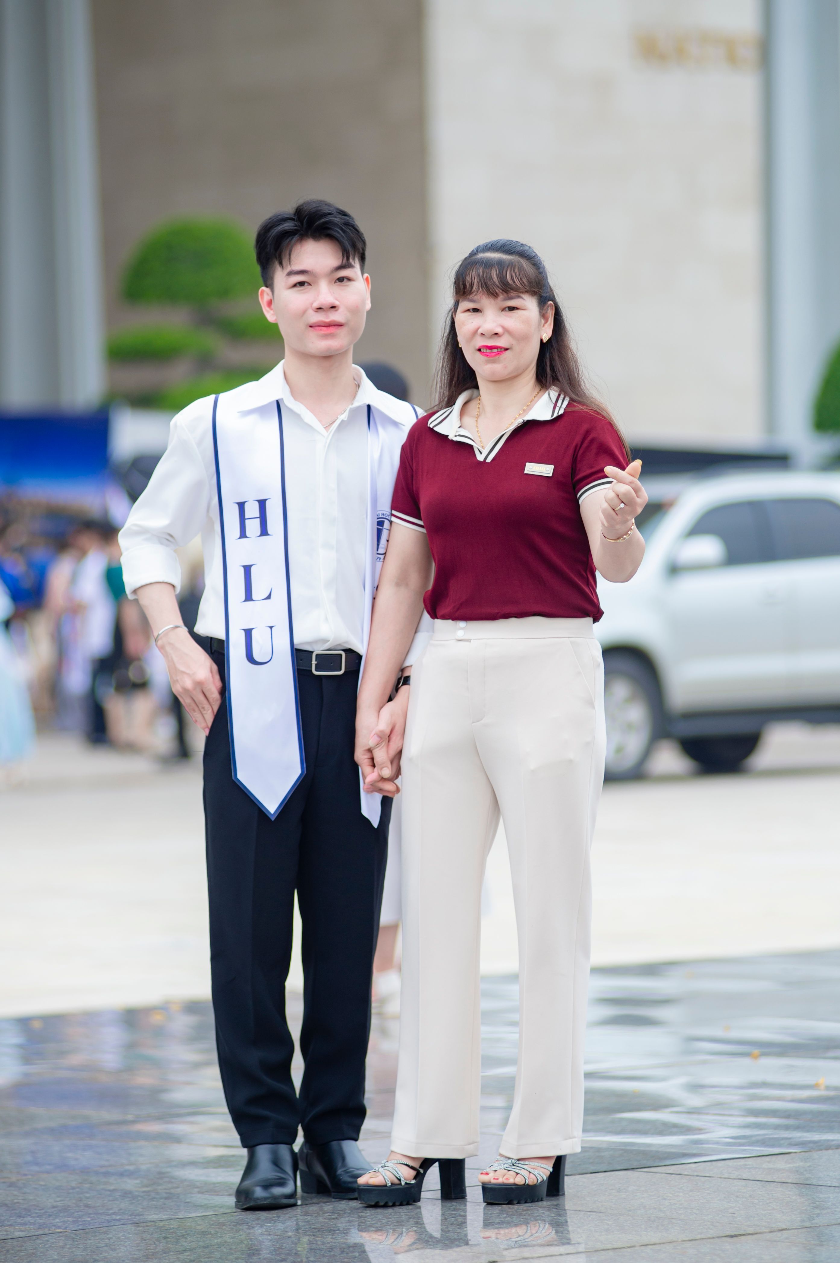 A young graduate with his family member celebrating at an outdoor venue in Hà Nội, Việt Nam.