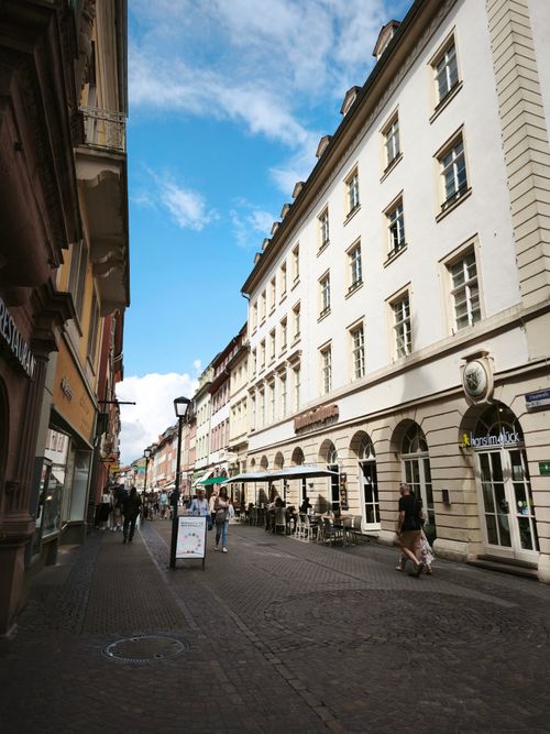 Free A vibrant street scene in Heidelberg, Germany, showcasing historic architecture and lively pedestrian activity. Stock Photo