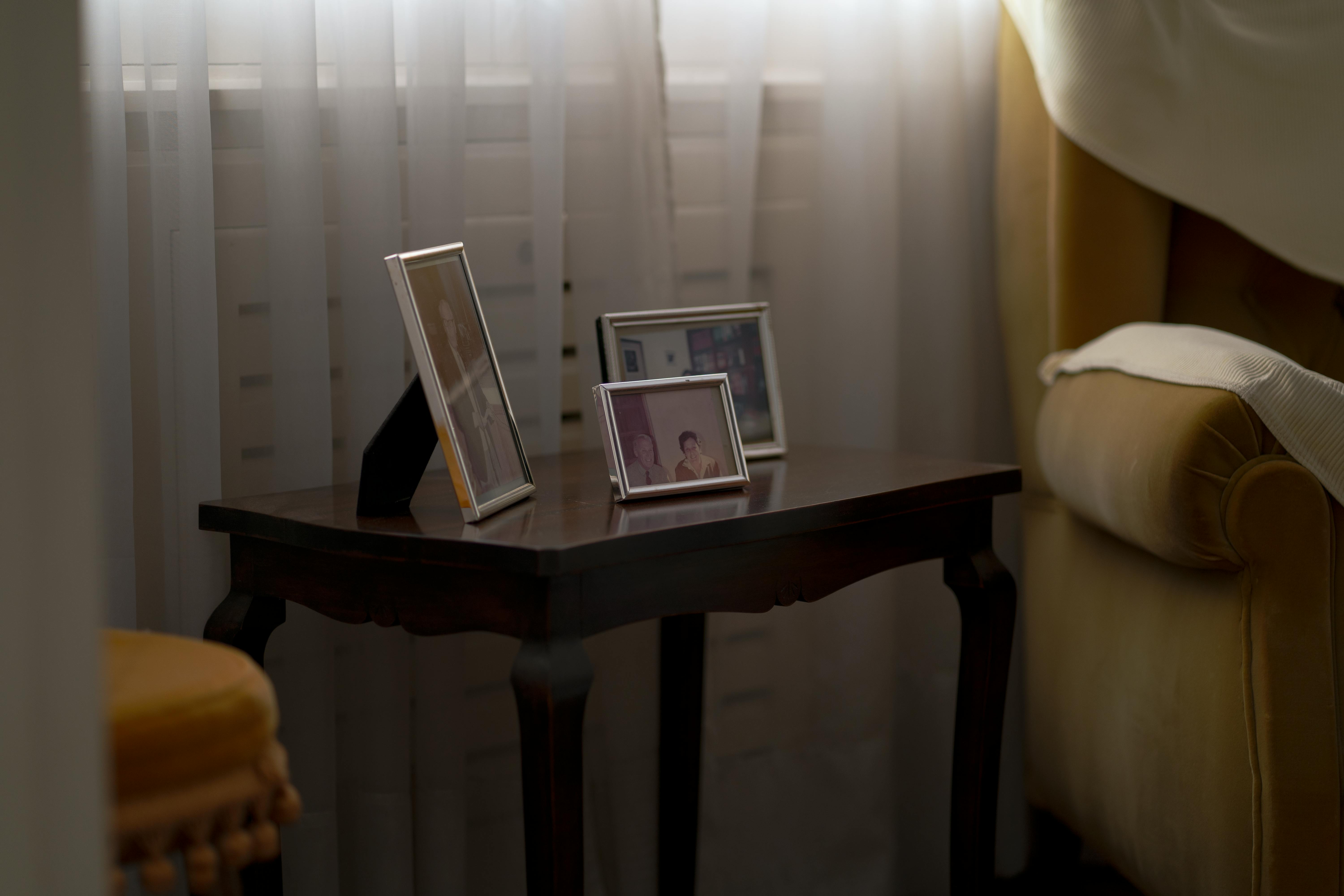 Bezpłatne Ciepły, przyjazny kącik ze zdjęciami w ramkach ustawionymi na stoliku przy oknie. Zdjęcie z galerii