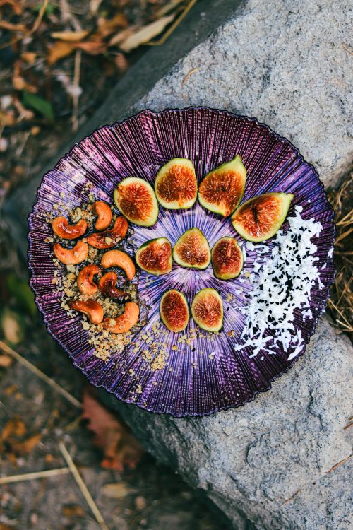 Free Tantalizing display of fresh figs, nuts, and coconut on a vibrant purple plate, perfect for summer meals. Stock Photo