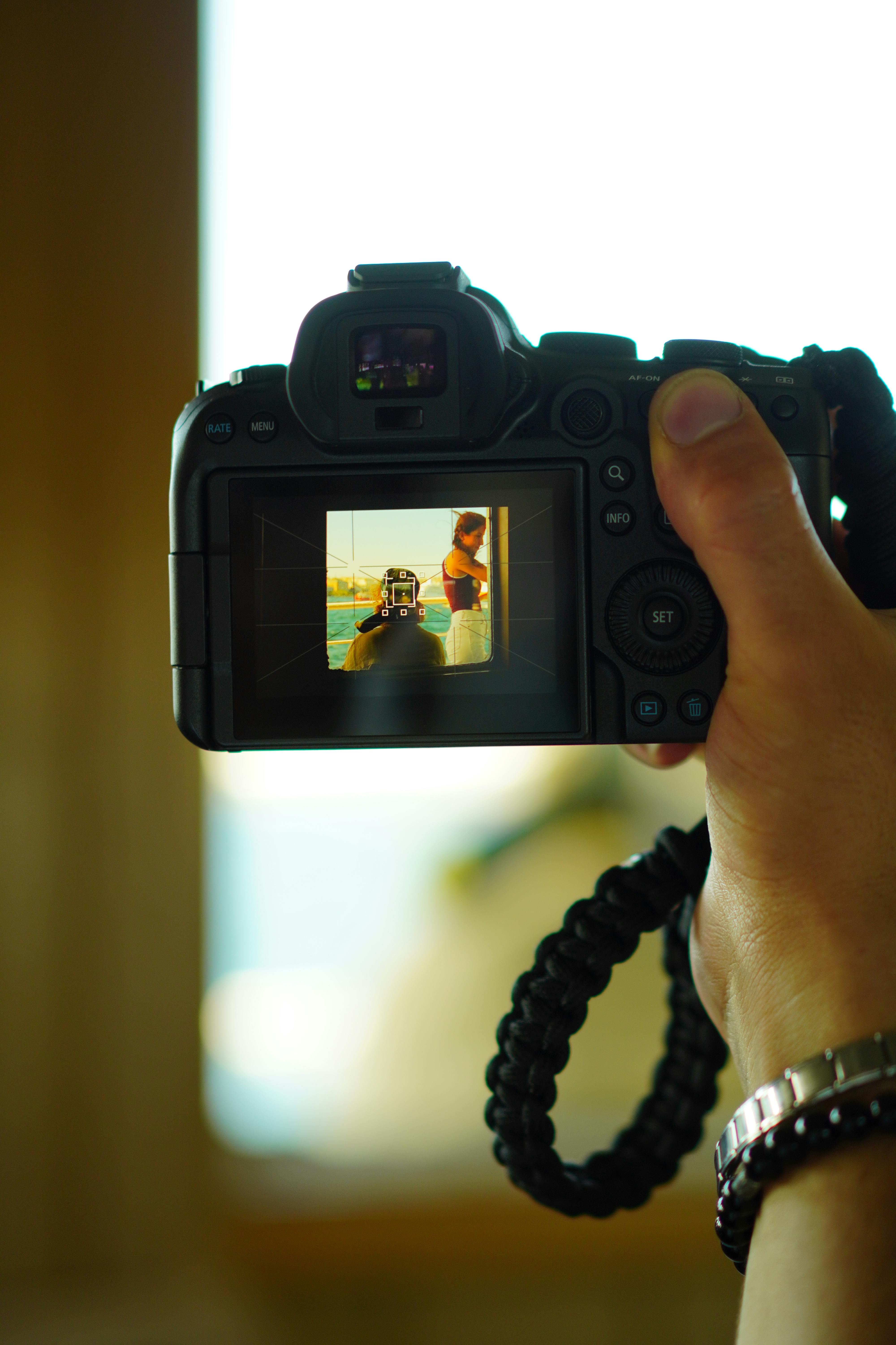 Free A camera screen shows a person posing for a photo in a vivid outdoor setting. Stock Photo
