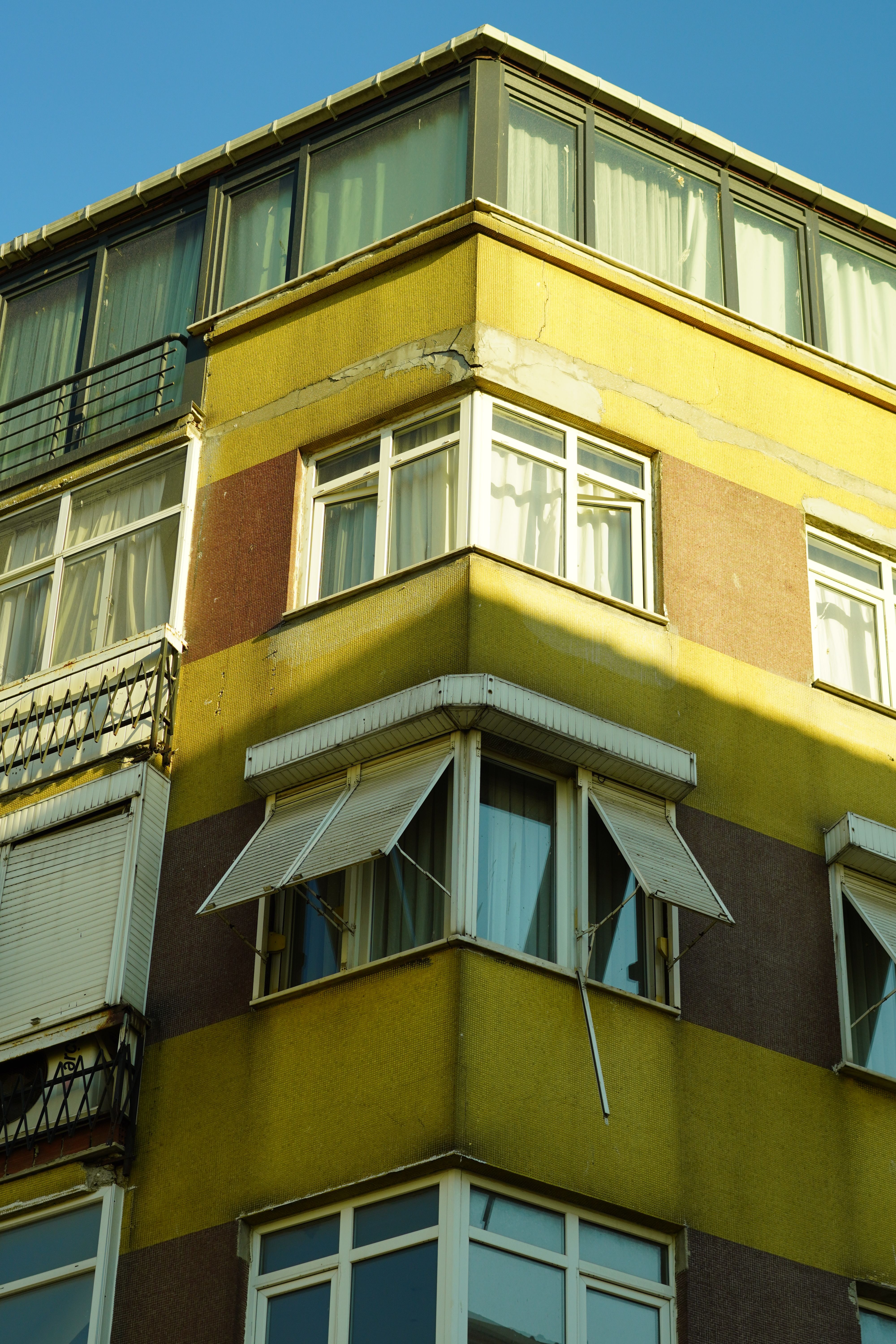 Corner view of a vibrant building with open window shutters, showcasing urban architecture.