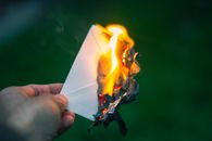 A captivating image of a hand holding a burning paper, symbolizing destruction or release. Perfect for themes of letting go.