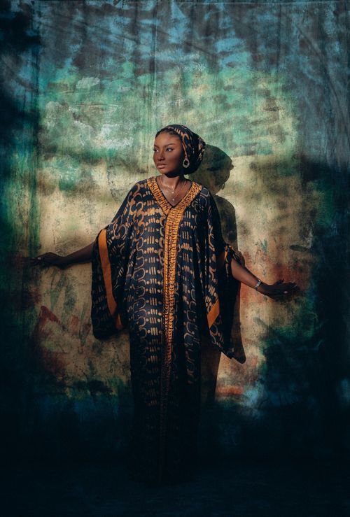 Free Striking photo of a woman in a traditional kaftan against a vibrant backdrop. Stock Photo