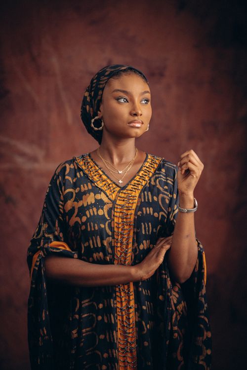 Free A woman in traditional clothing poses elegantly against a brown background. Stock Photo