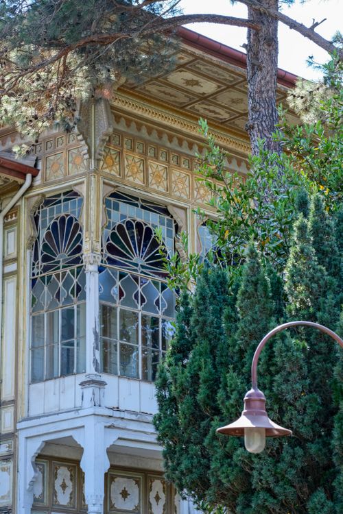 Free Detailed view of an ornate historic building facade framed by lush greenery. Stock Photo