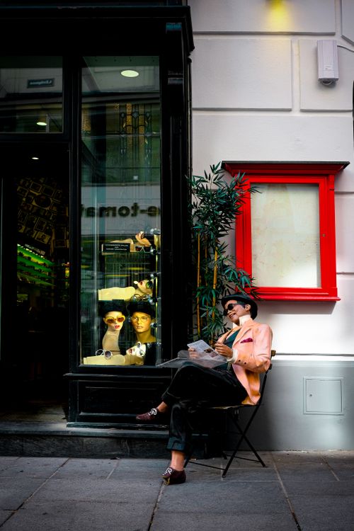 Free Stylish woman reading newspaper outside a fashionable boutique in cityscape. Stock Photo
