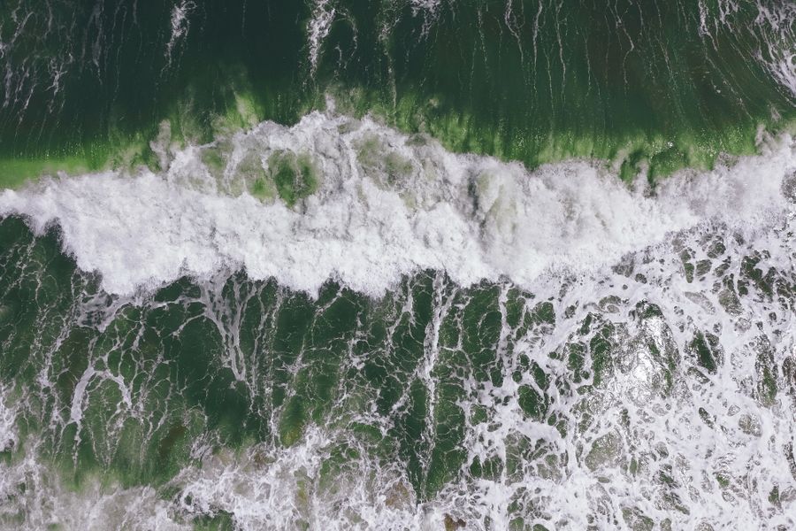White foam tracing patterns across deep green ocean water