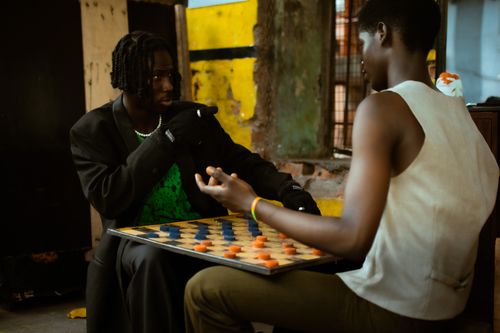 Free Two young men engage in a focused game of checkers, displaying strategy and concentration. Stock Photo