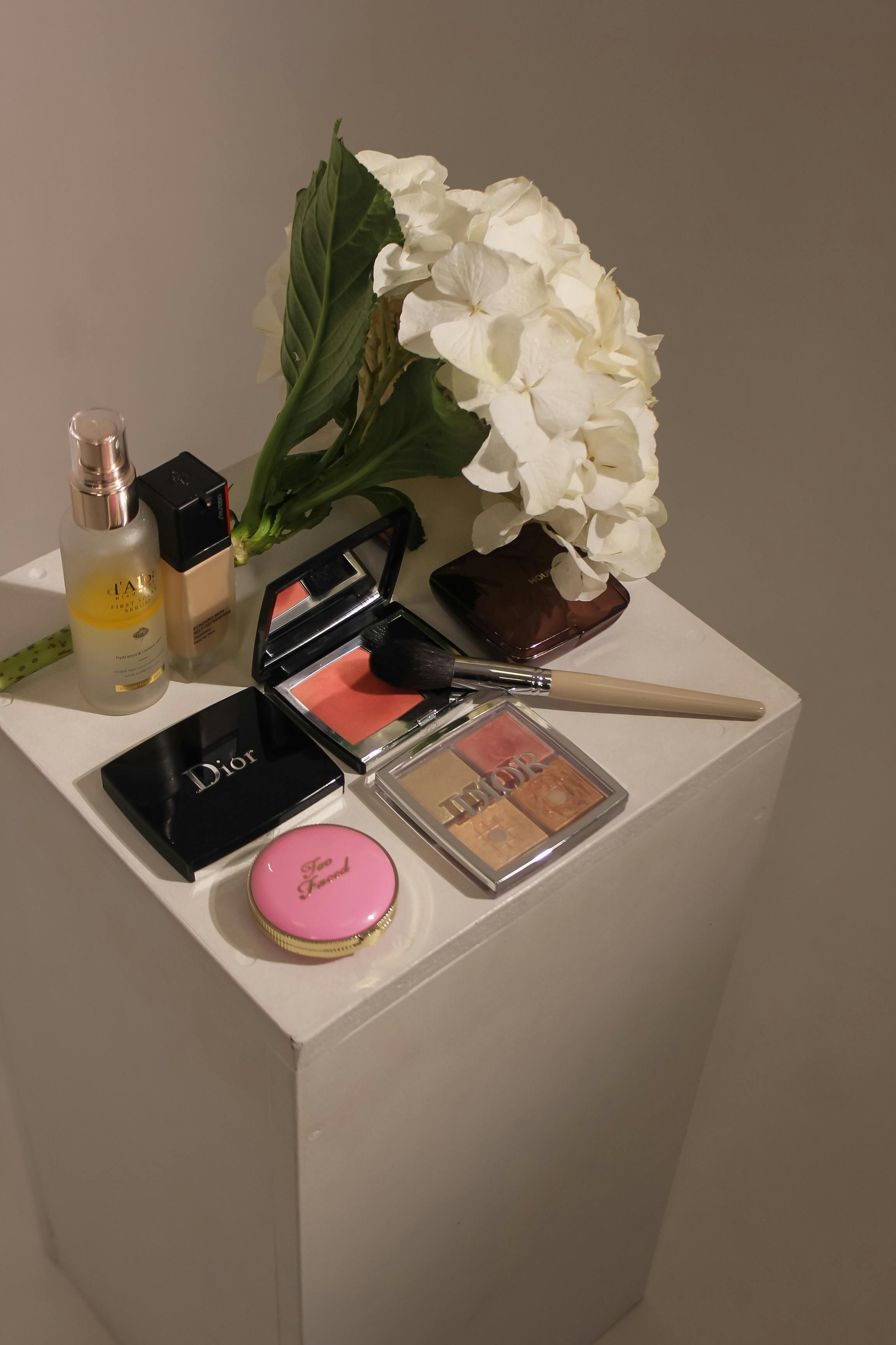 [ColoSach]-aesthetic-display-of-luxury-makeup-products-with-white-hydrangea-flowers-on-a-pedestal.