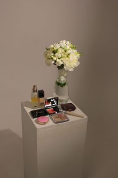 White floral bouquet with makeup set on pedestal, perfect for beauty and lifestyle themes.
