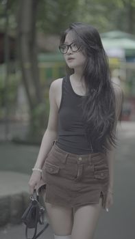 Young woman walking in a park, stylish attire, and relaxed poses represent modern urban lifestyle.