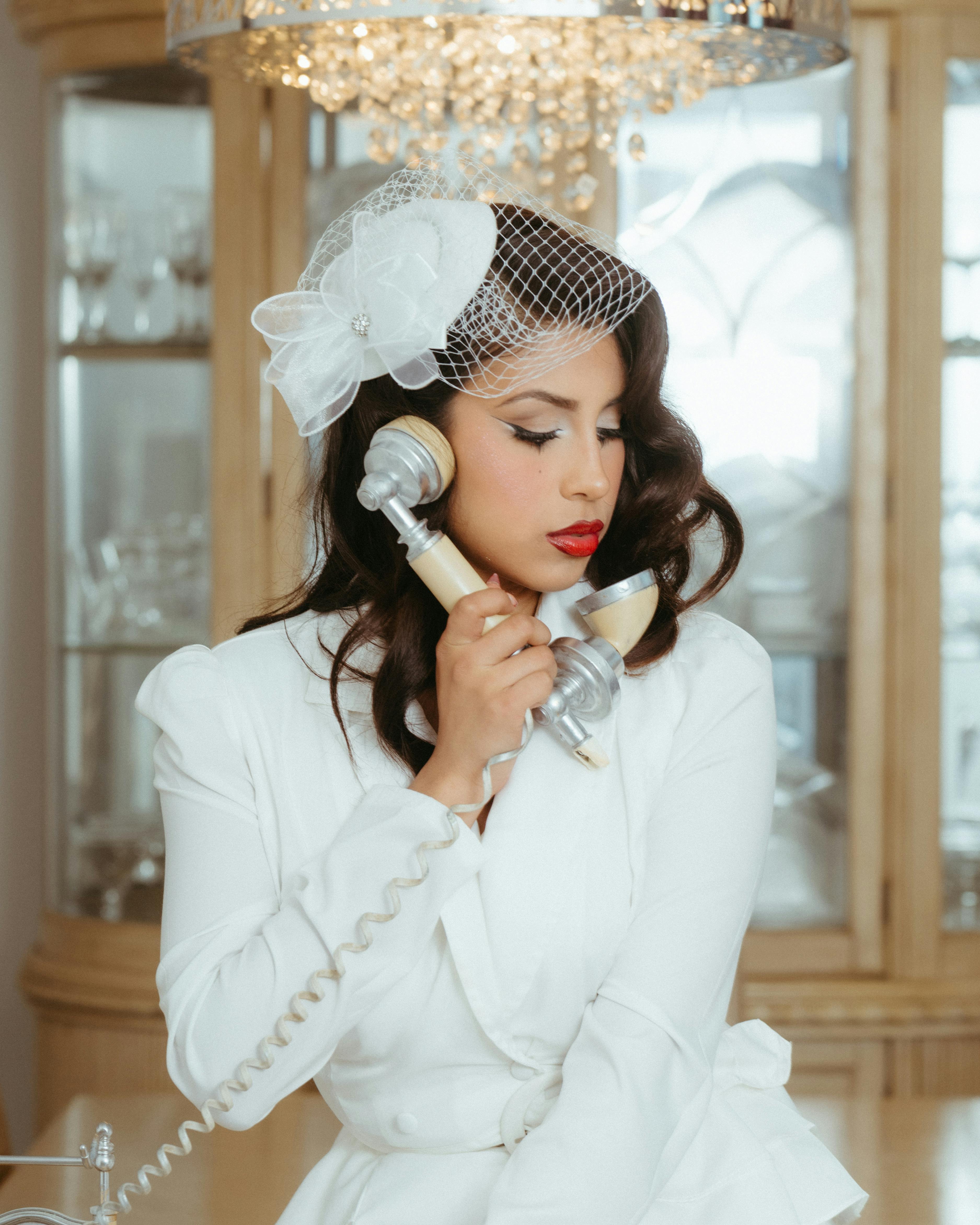 Elegant woman in vintage attire using a retro phone, evoking classic charm in an indoor setting.