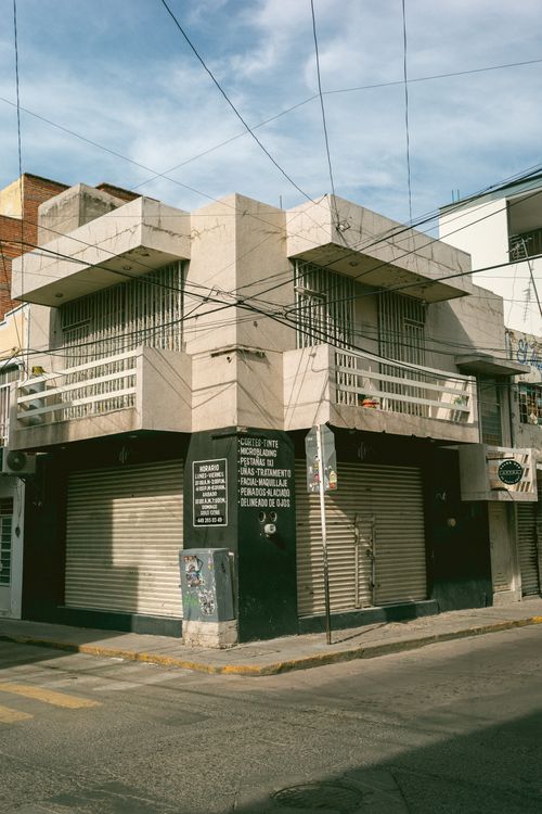 Free A classic urban building on a street corner with closed shutters and clear sky above. Stock Photo
