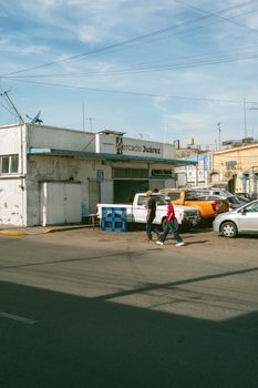 People and cars outside Mercado Juárez on a sunny day capturing urban life.