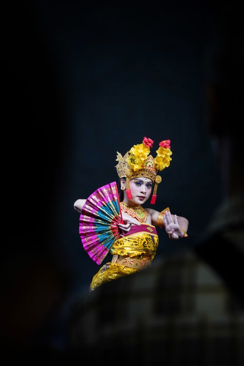 Free A Balinese dancer performs in colorful traditional costume and headpiece, holding a vibrant fan. Stock Photo