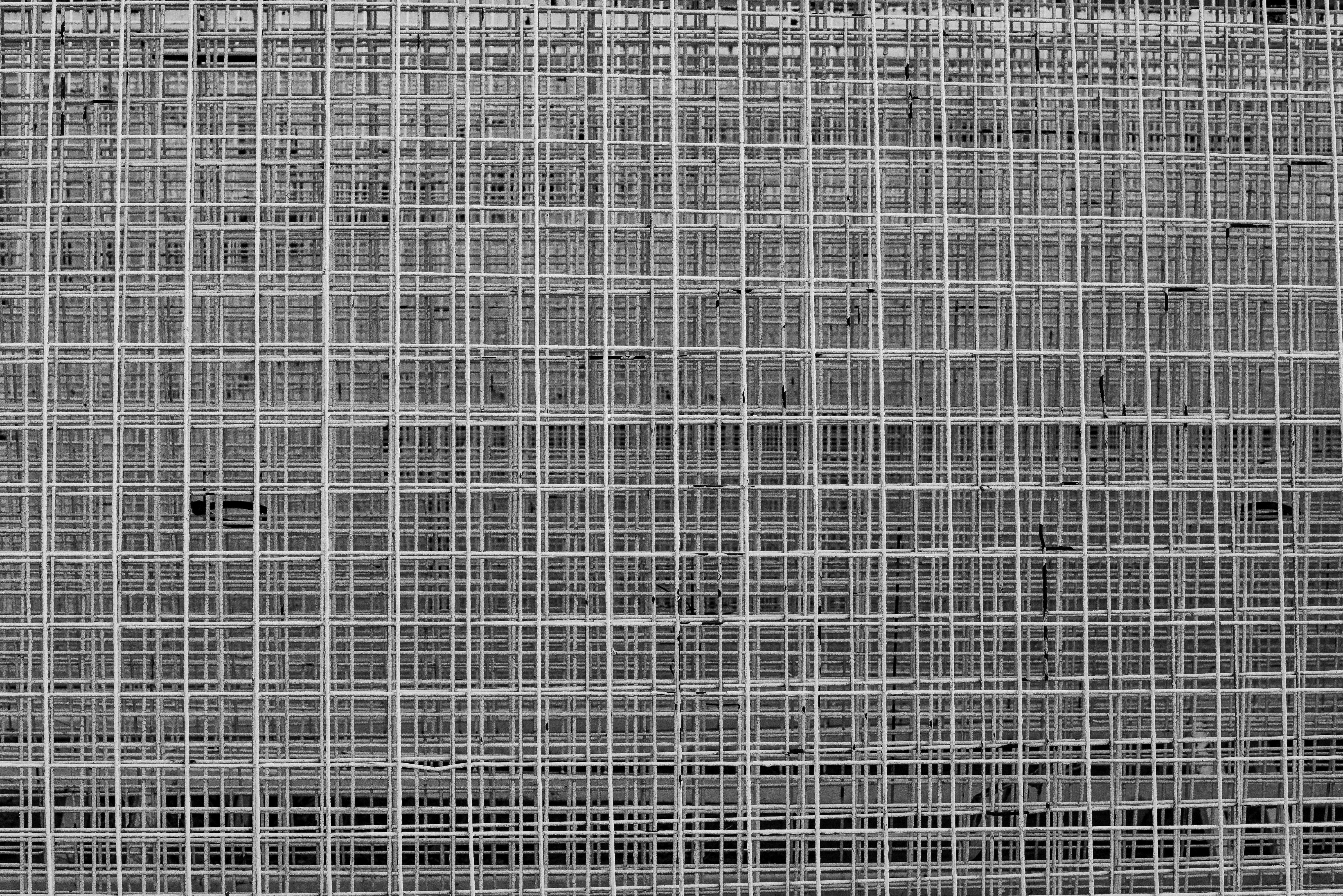 Gratis Una fotografia dettagliata in bianco e nero di un motivo geometrico a griglia metallica che crea una trama urbana. Foto a disposizione