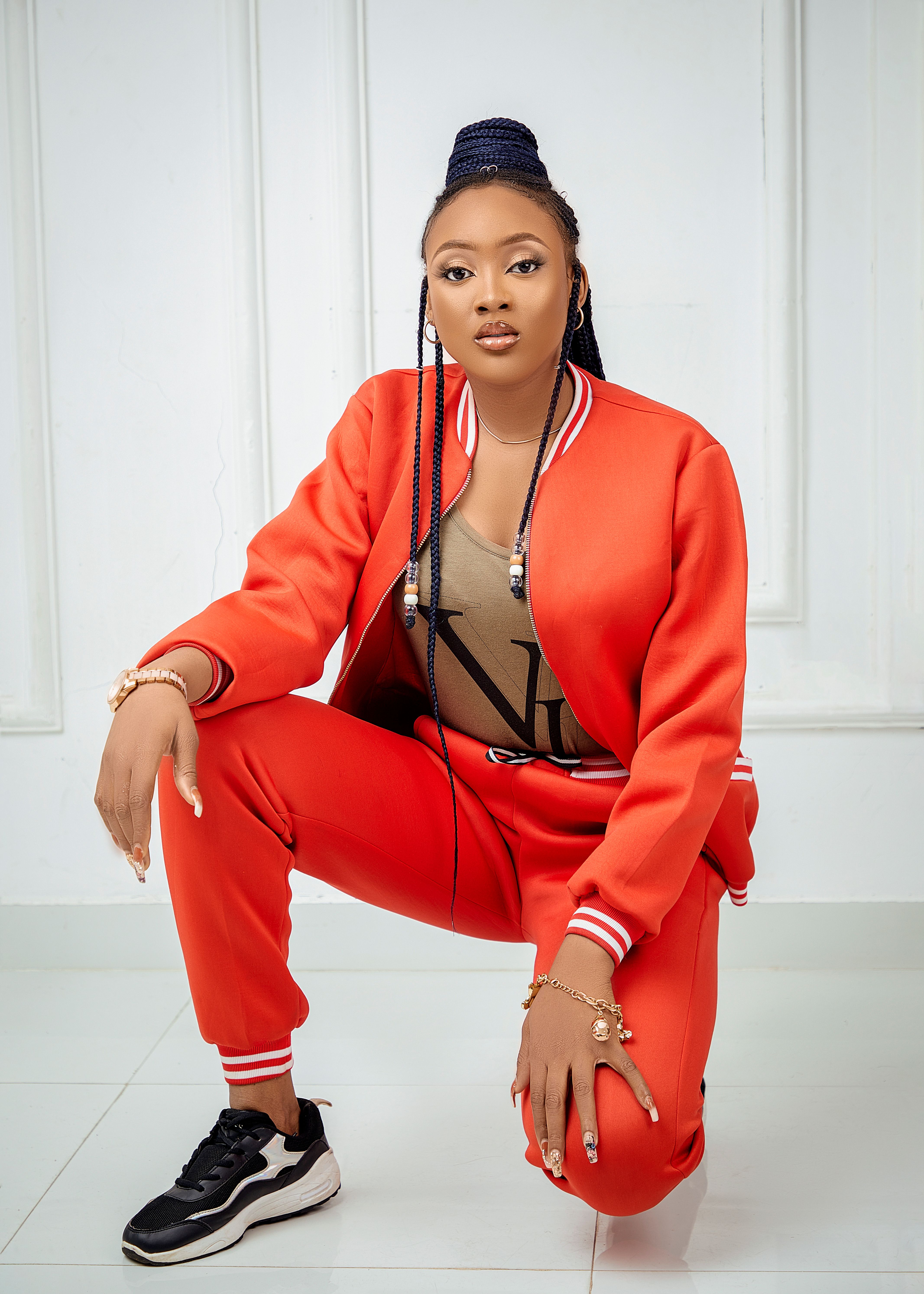 Stylish woman in red tracksuit posing confidently indoors. Casual yet chic look.