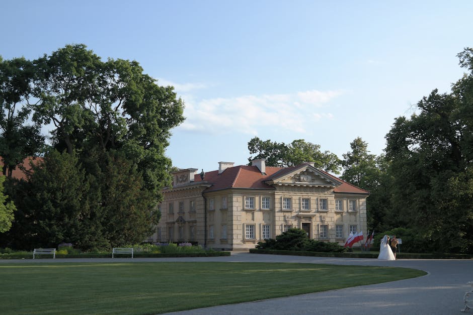 A beautiful mansion surrounded by gardens with a couple in wedding attire.