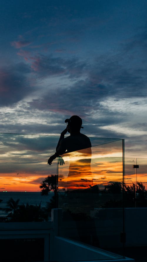 Free Person Standing Beside Glass Wall during Golden Hour Stock Photo